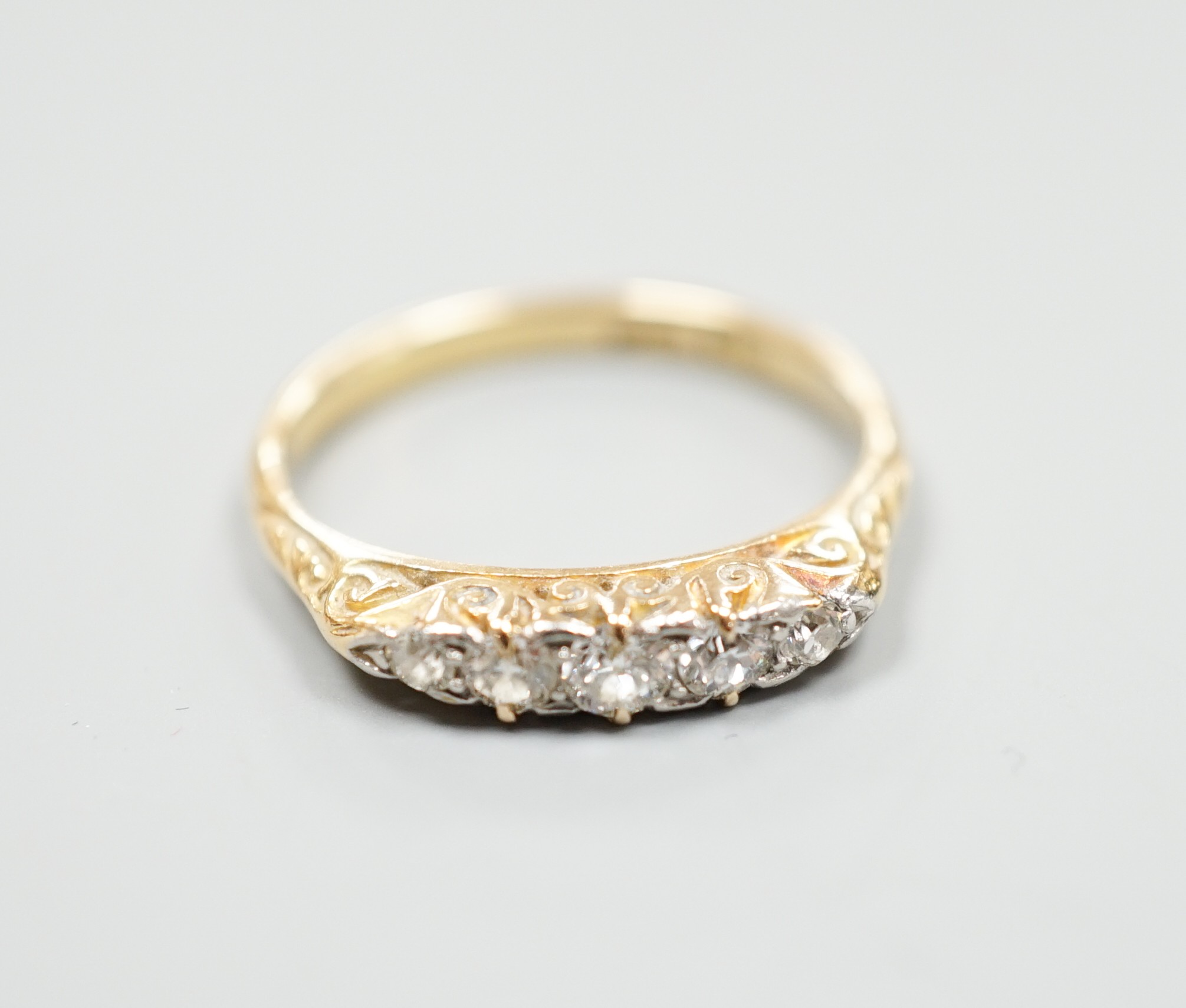 An 18ct and graduated five stone diamond set half hoop ring, size O, gross weight 3 grams.